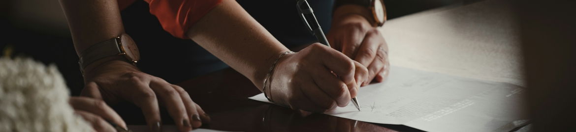 person-in-orange-long-sleeve-shirt-writing-on-white-paper.jpg person in orange long sleeve shirt writing on white paper